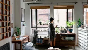 imagem de uma mulher de pijama com uma caneca na mão em um escritório dentro de sua casa.
